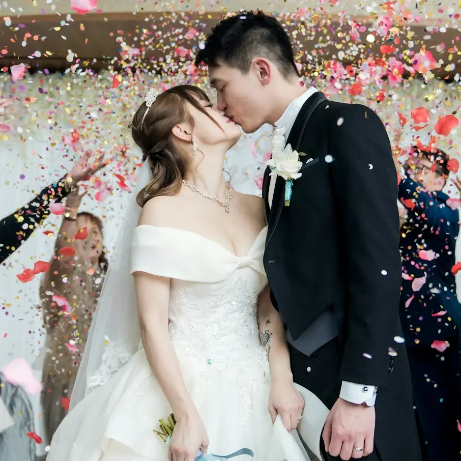 man in black suit kissing woman in white wedding dress